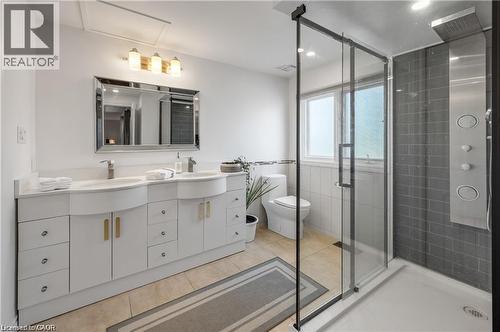Full bathroom featuring a dual-sink vanity with white cabinetry and chrome hardware, a glass-enclosed shower with a multi-function panel, and a toilet - 355 Edgehill Drive, Kitchener, ON 