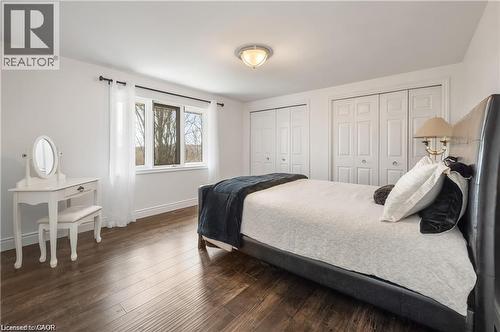 Spacious room featuring wood-finish flooring, two large bifold door closets, a multi-pane window with white trim, and a ceiling-mounted light fixture - 355 Edgehill Drive, Kitchener, ON 