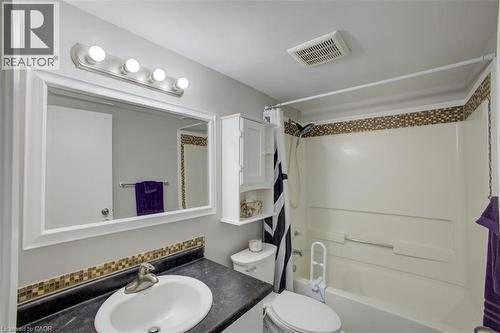 Contemporary bathroom featuring a vanity with a dark countertop and integrated sink, a large framed mirror, and a five-bulb vanity light fixture - 355 Edgehill Drive, Kitchener, ON 