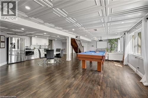 Spacious recreation room featuring wood-finish flooring, a contemporary kitchenette with stainless steel appliances, and an intricate coffered ceiling with recessed lighting - 355 Edgehill Drive, Kitchener, ON 