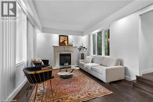 Living area featuring a detailed fireplace with a stone mantel, dark wood-finish flooring, recessed lighting, and multiple windows - 355 Edgehill Drive, Kitchener, ON 
