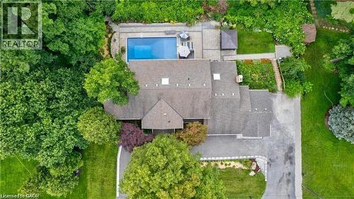 Extensive property featuring a large swimming pool, paver patio, a separate garden area with terraced steps, an attached main residence with a gabled roof, and a paved driveway - 355 Edgehill Drive, Kitchener, ON 