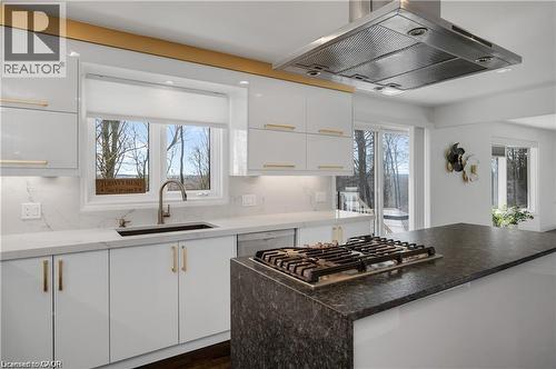Modern kitchen featuring a gas cooktop on a substantial island with dark stone countertops - 355 Edgehill Drive, Kitchener, ON 
