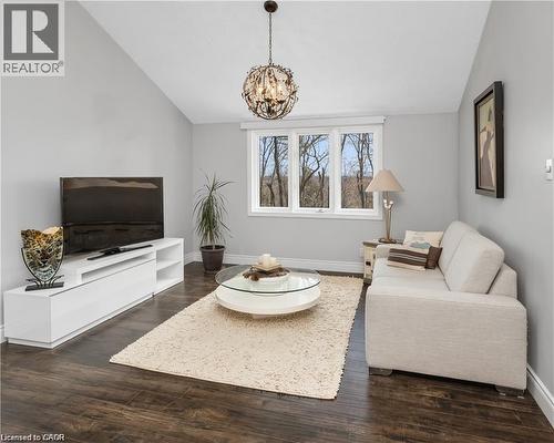 Vaulted ceiling living space featuring dark wood-finish flooring, a multi-pane window, and a decorative chandelier - 355 Edgehill Drive, Kitchener, ON 