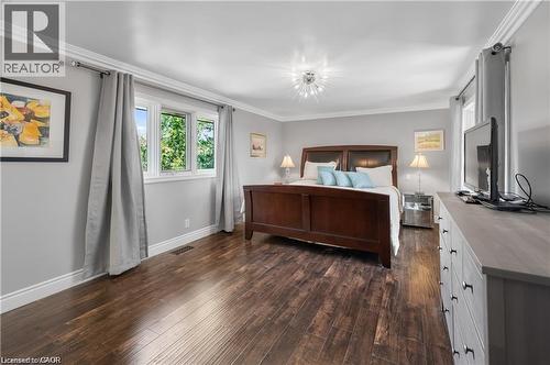 Spacious room featuring wood-finish flooring, a contemporary ceiling fixture, white baseboards, and crown molding - 355 Edgehill Drive, Kitchener, ON 