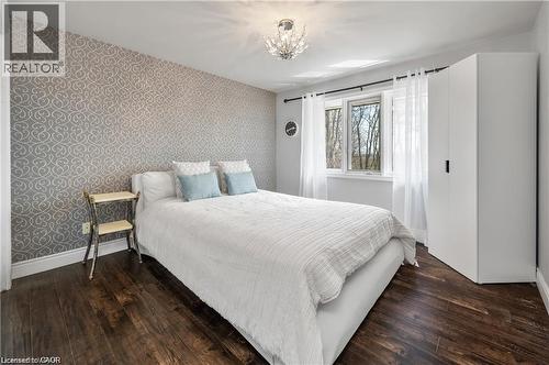 Bedroom with patterned accent wall, dark wood-finish flooring, and a large window - 355 Edgehill Drive, Kitchener, ON 