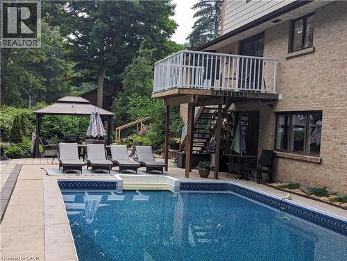 In-ground swimming pool with integrated steps, surrounded by stone patio decking - 355 Edgehill Drive, Kitchener, ON 