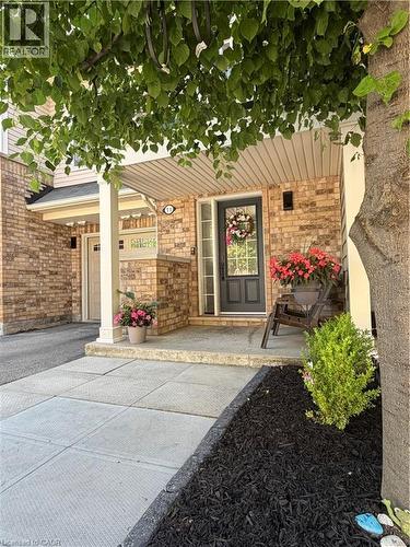 Brick facade with a covered entry, featuring a dark panel door and porch lighting - 7 Sirente Drive Unit# 11, Hamilton, ON - Outdoor