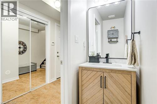 Modern vanity with a light wood-finish cabinet featuring a herringbone pattern, a white countertop, and a black framed mirror - 7 Sirente Drive Unit# 11, Hamilton, ON - Indoor