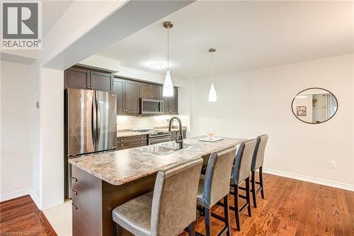 Open-concept kitchen featuring dark wood cabinetry, stainless steel appliances, and a light-toned backsplash - 7 Sirente Drive Unit# 11, Hamilton, ON - Indoor Photo Showing Other Room