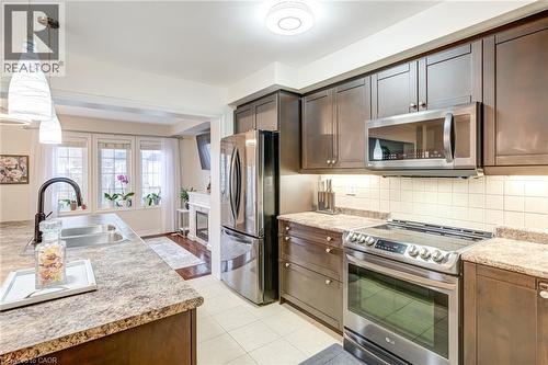 Contemporary kitchen featuring dark wood-finish cabinetry, stainless steel appliances, and light-toned countertops - 7 Sirente Drive Unit# 11, Hamilton, ON - Indoor Photo Showing Kitchen With Double Sink With Upgraded Kitchen