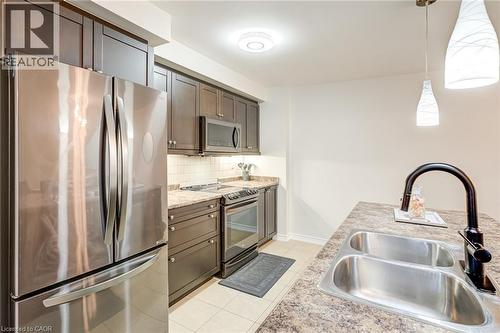 Modern kitchen featuring dark wood-finish cabinetry, stainless steel appliances, and contrasting light countertops - 7 Sirente Drive Unit# 11, Hamilton, ON - Indoor Photo Showing Kitchen With Double Sink