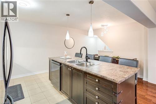 Kitchen island featuring a double-basin stainless steel sink, dark cabinetry, and a stone-finish countertop - 7 Sirente Drive Unit# 11, Hamilton, ON - Indoor Photo Showing Kitchen With Double Sink