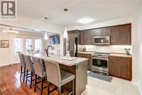 Kitchen featuring a large island with sink, ample dark wood cabinetry, stainless steel appliances, and light-colored countertops - 7 Sirente Drive Unit# 11, Hamilton, ON - Indoor Photo Showing Kitchen With Upgraded Kitchen