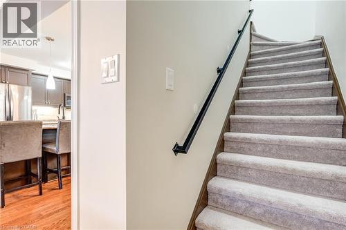 Carpeted staircase featuring a black metal handrail and light neutral wall finishes - 7 Sirente Drive Unit# 11, Hamilton, ON - Indoor Photo Showing Other Room