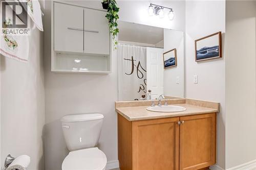 Bathroom featuring a wood-finish vanity with a light-toned countertop, an undermount sink, and a large wall-mounted mirror - 7 Sirente Drive Unit# 11, Hamilton, ON - Indoor Photo Showing Bathroom