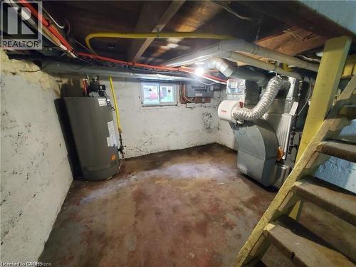 Basement utility area featuring a hot water heater, forced air furnace with ductwork, and exposed ceiling joists with visible wiring and plumbing - 94 Brook Street, Simcoe, ON - Indoor Photo Showing Basement