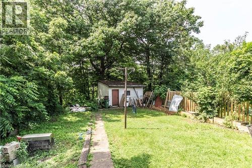 Expansive backyard featuring a central lawn, concrete pathway, and mature trees - 404 Queenston Road, Hamilton, ON 