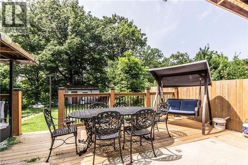 Expansive outdoor deck featuring wood decking, wood railings with black balusters, and a privacy fence - 404 Queenston Road, Hamilton, ON 