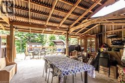 Covered outdoor living space featuring exposed wood beam construction and a corrugated metal roof - 