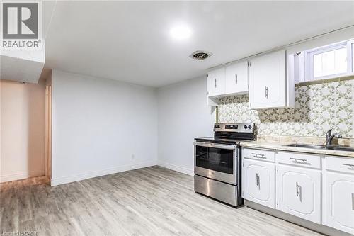 Kitchen area featuring white cabinetry, a stainless steel range, and a single-basin sink - 404 Queenston Road, Hamilton, ON 