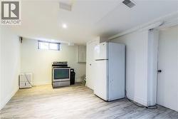 Spacious utility area featuring wood-finish flooring, a white refrigerator, and a freestanding electric range - 