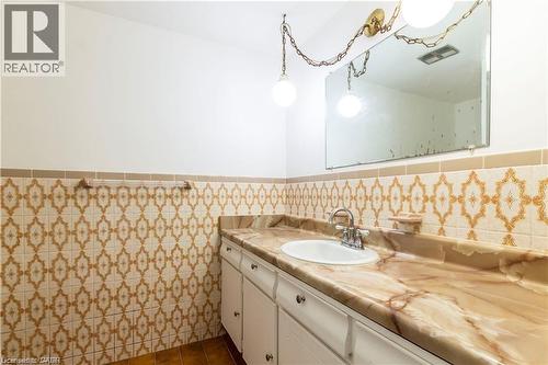 Bathroom vanity with an integrated sink, a polished chrome faucet, and a patterned stone-look countertop - 404 Queenston Road, Hamilton, ON 