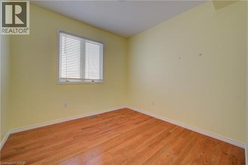 Bright interior space featuring wood-finish flooring, light-colored walls, white trim, and a window with blinds - 180 Arthur Fach Drive, Cambridge, ON 