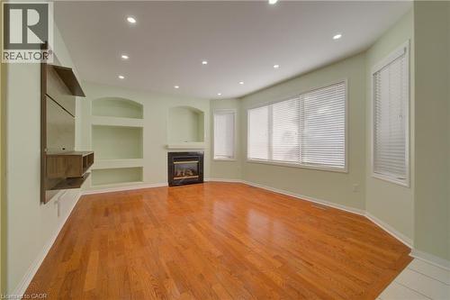 Living area featuring wood-finish flooring, a built-in fireplace with a dark surround, recessed lighting, and a bay window with blinds - 180 Arthur Fach Drive, Cambridge, ON 
