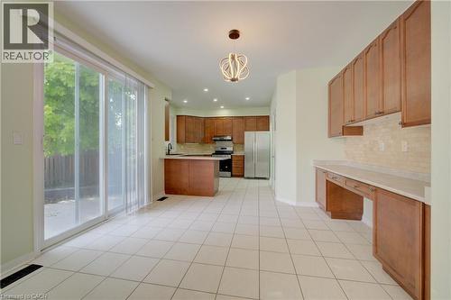 Open-concept kitchen and dining area featuring light-toned tile flooring and a sliding glass door to the exterior - 180 Arthur Fach Drive, Cambridge, ON 