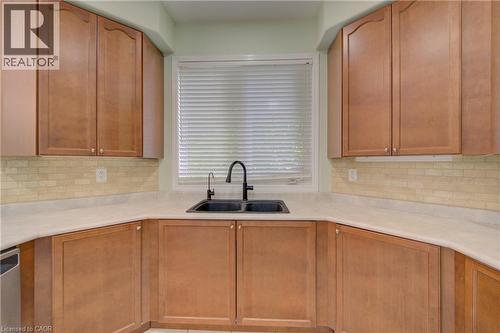 Kitchen featuring wood cabinetry, light-toned countertops, and a subway tile backsplash - 180 Arthur Fach Drive, Cambridge, ON 