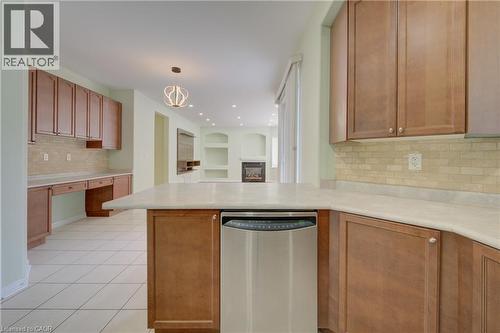 Kitchen featuring wood-finish cabinetry, light-toned countertops, and a tiled backsplash - 180 Arthur Fach Drive, Cambridge, ON 