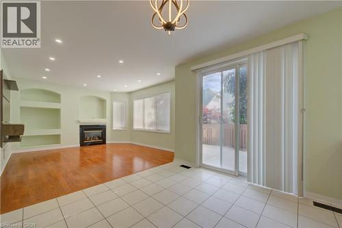 Spacious interior featuring a fireplace with a dark surround, built-in shelving, bay windows with blinds, and recessed lighting - 180 Arthur Fach Drive, Cambridge, ON 