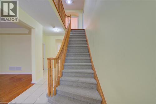 Carpeted staircase featuring a light wood-finish railing and balusters - 180 Arthur Fach Drive, Cambridge, ON 