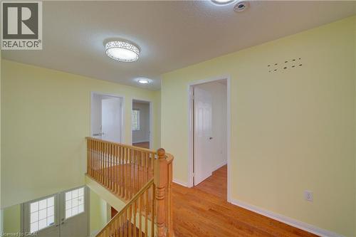 Second-story landing featuring wood-finish flooring, a wood baluster railing, and recessed lighting - 180 Arthur Fach Drive, Cambridge, ON 