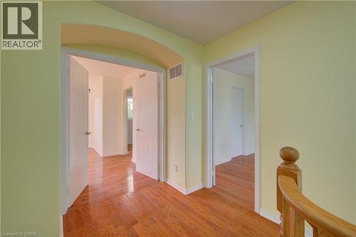 Hallway featuring hardwood flooring, light-toned walls, white trim, and an arched doorway - 180 Arthur Fach Drive, Cambridge, ON 