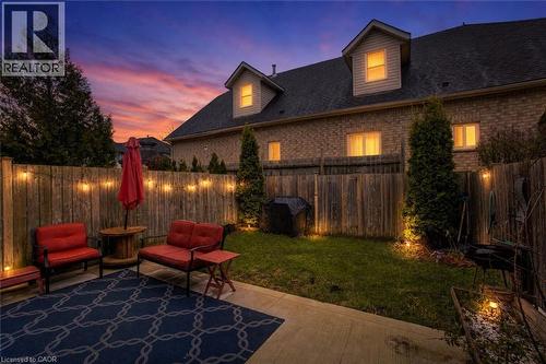 Private backyard featuring a concrete patio, string lighting, and mature landscaping - 53 Prosperity Drive, Kitchener, ON 
