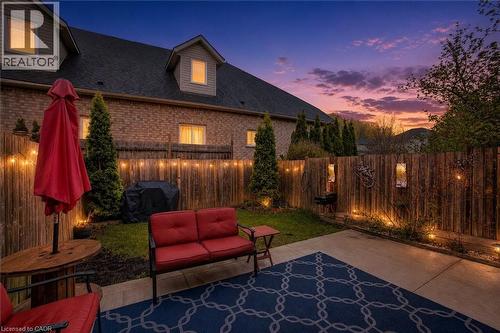 Private outdoor patio area featuring concrete paving, a wood privacy fence, and string lighting - 53 Prosperity Drive, Kitchener, ON 