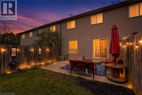 Private fenced backyard featuring a concrete patio, string lighting, and direct access to the interior via sliding glass doors - 53 Prosperity Drive, Kitchener, ON 
