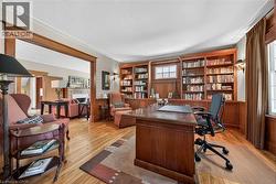 Dedicated study featuring extensive built-in custom wood cabinetry and shelving, hardwood flooring, and crown molding - 