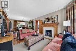 Living area featuring a wood-mantled fireplace with a tiled surround, recessed lighting, and wood-finish flooring - 