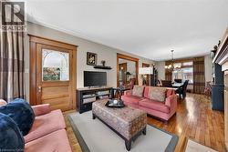 Hardwood flooring extends throughout this living space, featuring a decorative glass entry door with wood trim, crown molding, and a built-in fireplace mantel - 