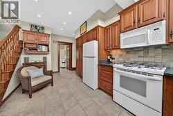 Kitchen featuring wood cabinetry, a tiled backsplash, and stone countertops - 