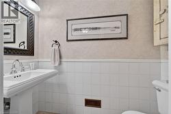 Pedestal sink with chrome faucet, white square wall tiling, and textured wall finish - 