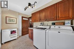 Functional main floor laundry area featuring upper and lower wood cabinetry, a utility sink, and tile flooring - 