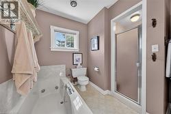 Bathroom featuring a jetted tub, a separate glass-enclosed shower, a standard toilet, and a window for natural light - 