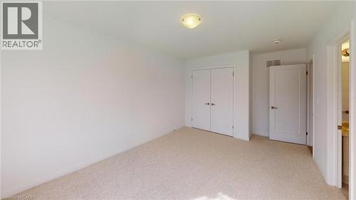 Carpeted room featuring white walls, a flush-mount ceiling light, and two white doors with polished hardware - 200 Cittadella Boulevard, Hamilton, ON 