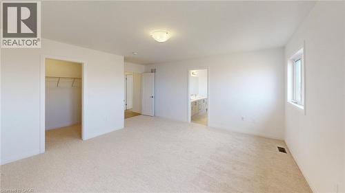 Carpeted room featuring a ceiling-mounted light fixture, white walls, and a window providing natural illumination - 200 Cittadella Boulevard, Hamilton, ON 