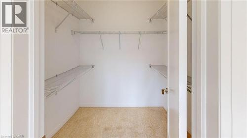 Walk-in closet featuring white wire shelving, hanging rods, and light-toned carpeting - 200 Cittadella Boulevard, Hamilton, ON 