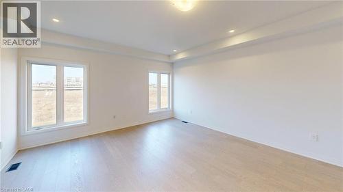 Spacious room featuring light wood-finish flooring, multiple windows, and a tray ceiling with recessed lighting - 200 Cittadella Boulevard, Hamilton, ON 